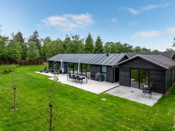 A modern house with a patio area featuring outdoor furniture and a barbecue.