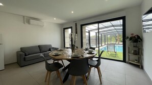 A modern dining area with a round table, four chairs, and a grey sofa.