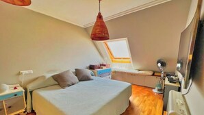 Une chambre à coucher comprenant un lit, des tables de chevet, un bureau, une chaise, une fenêtre et un ventilateur de plafond.