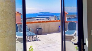 Un balcon avec vue sur la mer, une poubelle et deux chaises.