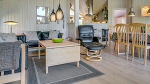 A modern living room with a sofa, a dining table, and a kitchen area in the background.