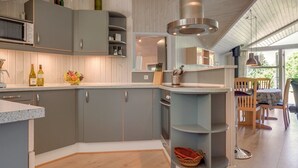 A modern kitchen with grey cabinets, a central island, and a dining area with wooden chairs and a table.