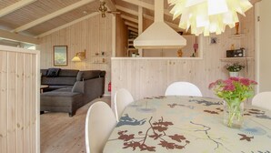 A cozy room with a wooden ceiling, a sofa, a dining table with chairs, and a hanging light fixture. - "Siegrid" - 250m from the sea by Interhome (Hals)