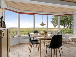 Uma sala de jantar com uma mesa grande, cadeiras e vista para o exterior.
