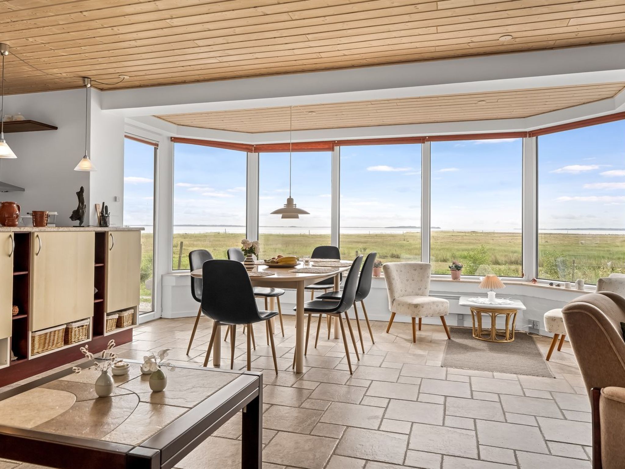A dining area with a large window, a table, chairs, and a view of the landscape.