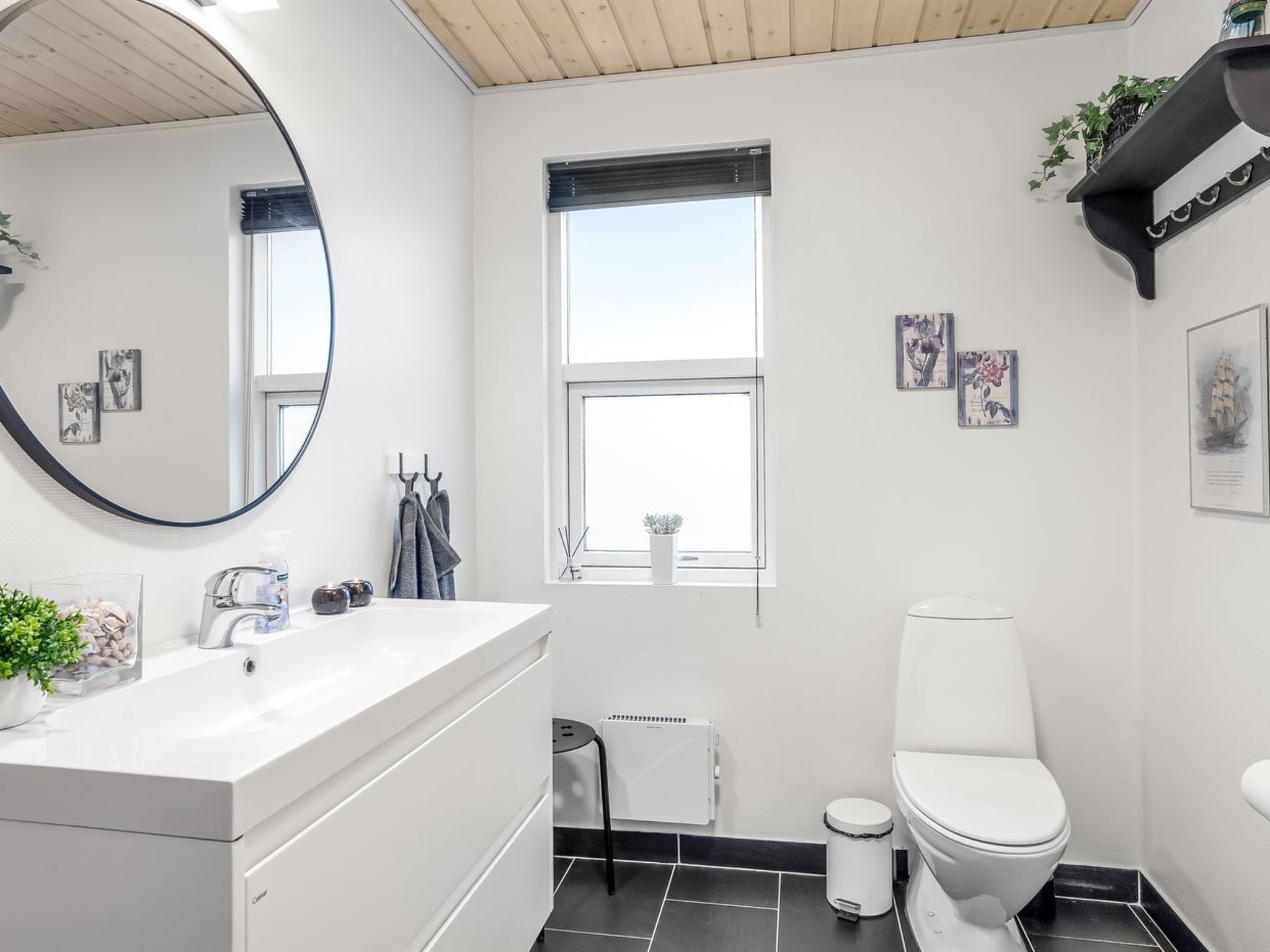 Un baño moderno con un lavabo blanco, un inodoro, un ventanal y radiadores.