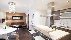 A modern kitchen with a central island, built-in appliances, and a dining area with a sofa and table. - Magnifique 2 Pièces Parc Monceau Paris 8 (Paris)