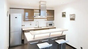 A modern kitchen with a central island, stainless steel appliances, and a minimalist design. - Magnifique 2 Pièces Parc Monceau Paris 8 (Paris)
