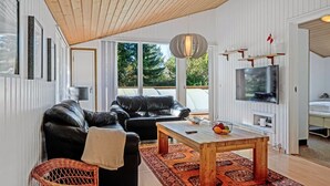 Een moderne woonkamer met een leren bank, een houten salontafel en een groot raam met uitzicht op de omgeving.