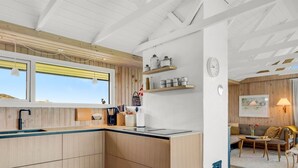 Une cuisine moderne avec des meubles en bois, un four encastré et une fenêtre donnant sur un paysage pittoresque.