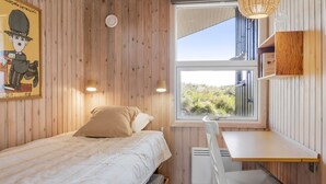 Une pièce confortable avec un lit, un bureau et une fenêtre donnant sur un paysage verdoyant.