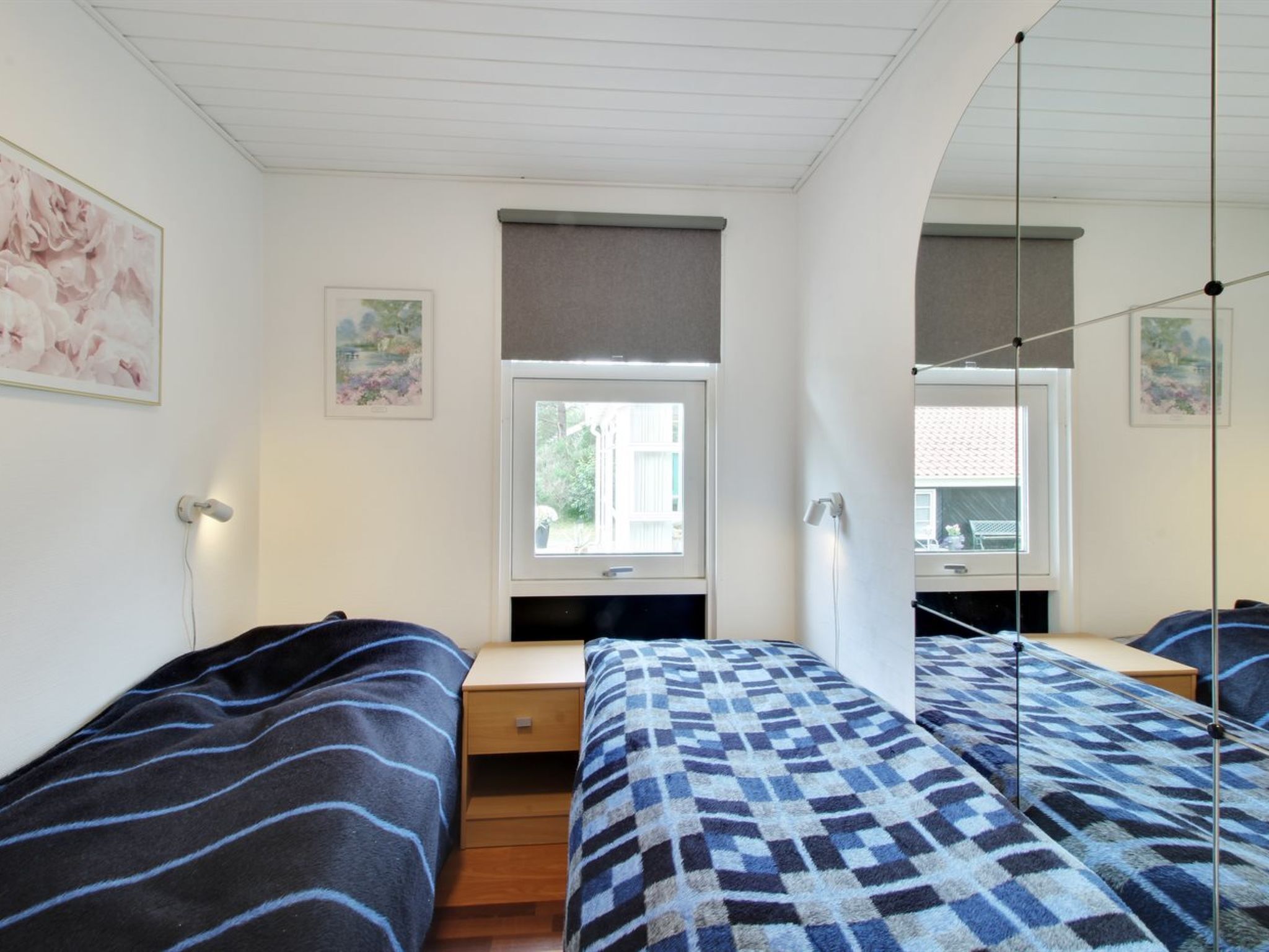 Ett rum med två sängar, ett fönster och ett skrivbord.