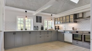 Een moderne keuken met grijze kastjes, witte aanrechtbladen en een dakraam.