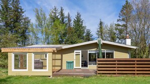 Ett envåningshus med en inglasad veranda, ett litet garage som är sammanbyggt med huset och en inhägnad trädgård.
