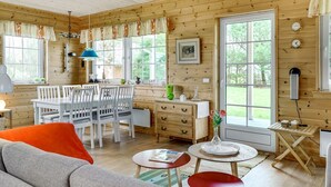 A cozy cabin interior with a dining area, a sofa, and a small table with a book.