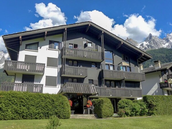 Um hotel com várias andares e varandas, com montanhas ao fundo.