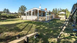 A mobile home with a large glass windowed section, a chimney, and a small deck area.