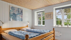 Una habitación con una cama de madera, papel tapiz a rayas y una ventana con vistas a la vegetación.