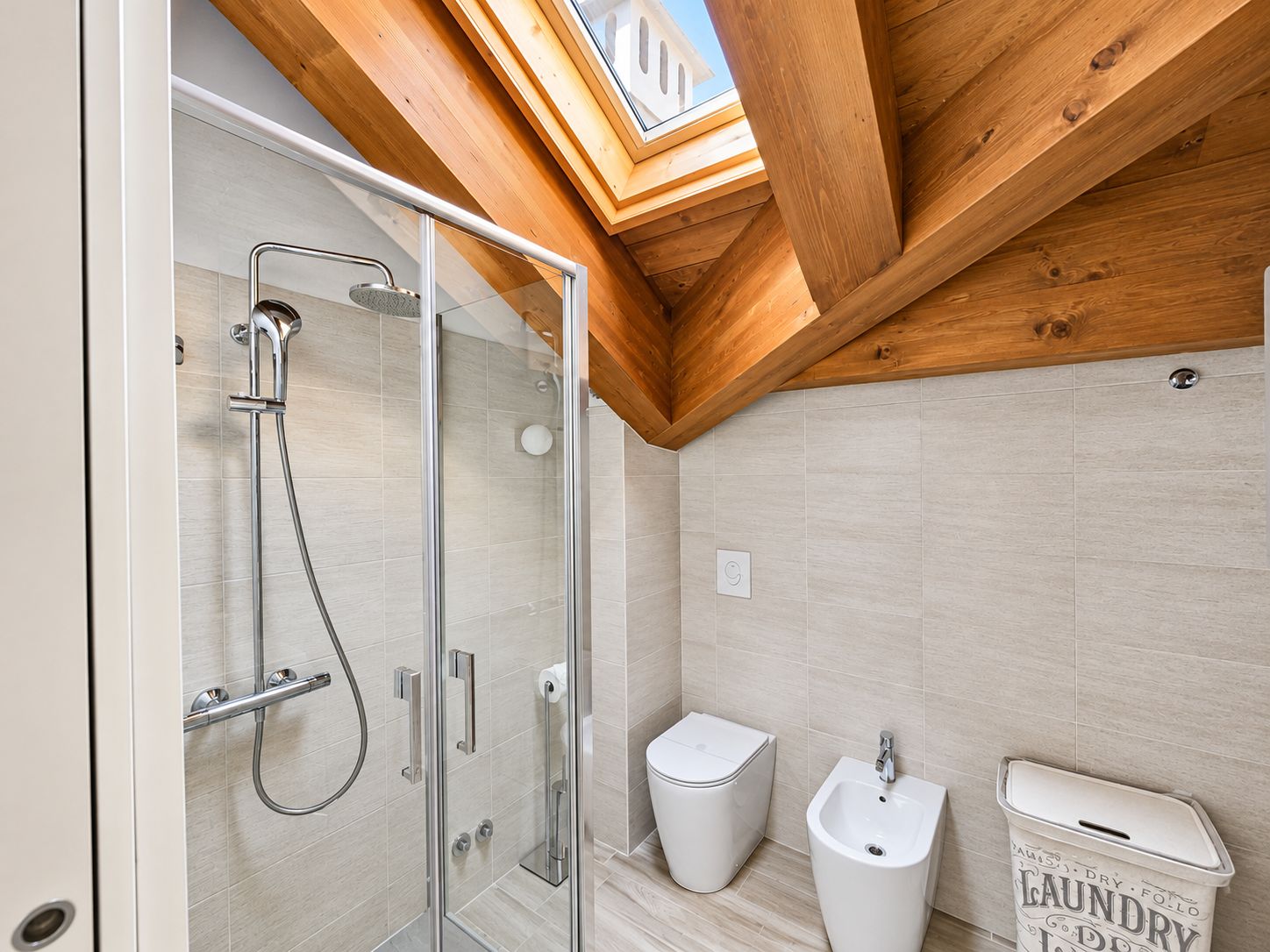 Une salle de bain moderne avec une douche à parois de verre, des toilettes, un bidet et un panier à linge.