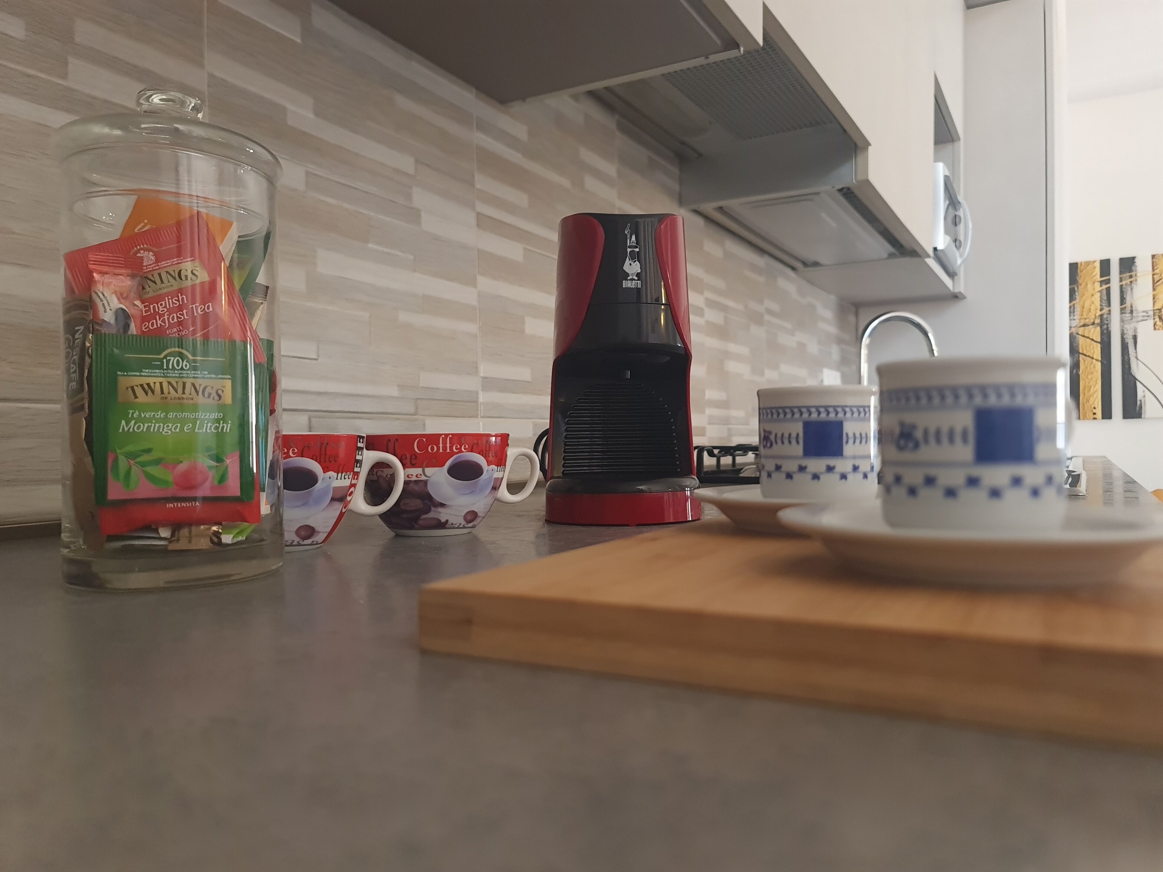En køkkenbordplade med en kaffemaskine, to kaffekopper, et glas med te og en keramikkop.
