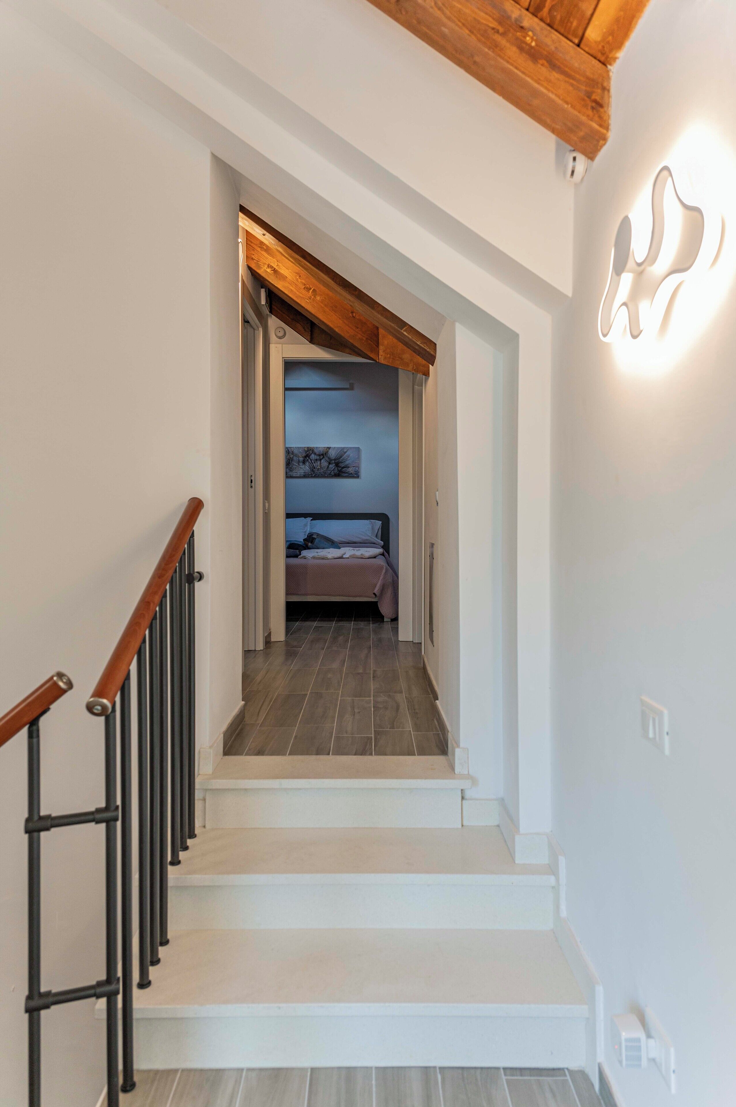 Un escalier menant à une chambre à coucher équipée d’un lit et d’une table de chevet.