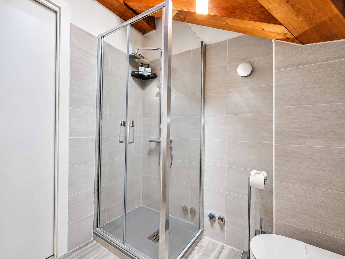 Une salle de bain moderne dotée d’une douche à parois de verre, de toilettes et d’un distributeur de serviettes.