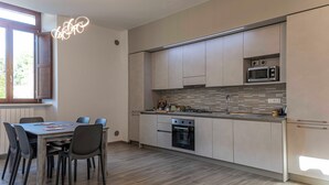 Een moderne keuken met een eethoek, met een ingebouwde oven, magnetron en een groot raam dat voor natuurlijk licht zorgt.
