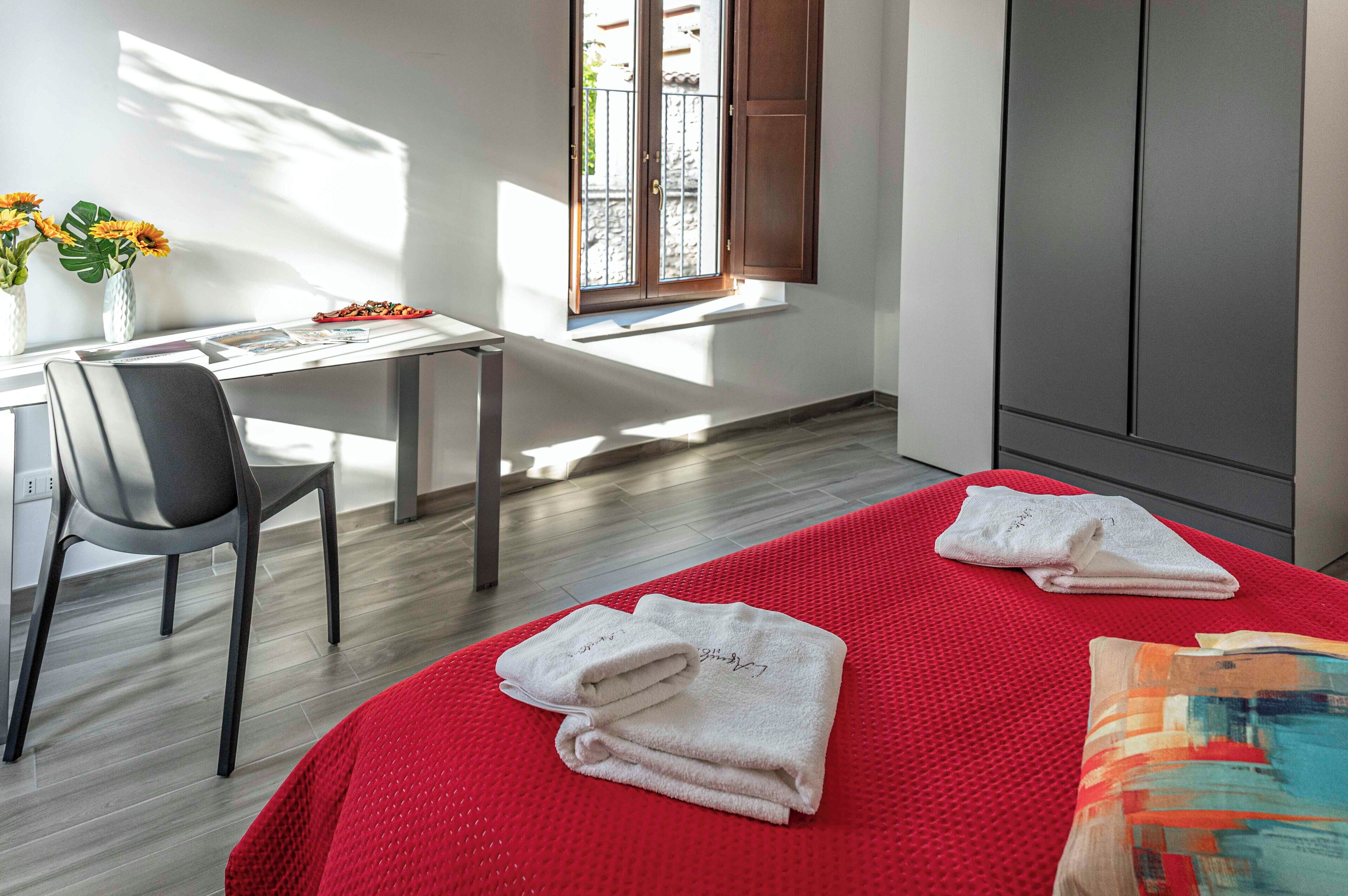 Habitación de hotel con cama, escritorio, silla, ventana con vistas y armario.