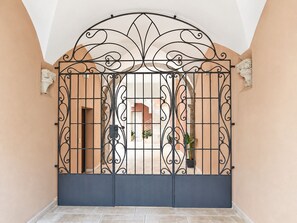 A gated entrance with a decorative metal gate, a tiled floor, and a beige wall. - *4 double bedrooms *fully equipped kitchen *2 living rooms with smart TVs *air conditioning (L'Aquila)