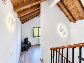 A modern interior with a wooden staircase, a flat-screen TV, and a window with a view of greenery. - *4 double bedrooms *fully equipped kitchen *2 living rooms with smart TVs *air conditioning (L'Aquila)