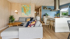 Un salon moderne avec un canapé gris, une table ronde en bois et une carte accrochée au mur.