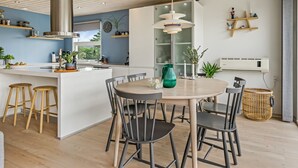 Une cuisine moderne dotée d’un îlot central, de tabourets en bois et d’une table à manger avec des chaises.