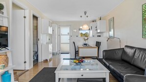 A modern living room with a glass coffee table, a black leather sofa, and a dining area with a white table and chairs. - "Dafna" - 100m from the sea by Interhome (Hals)