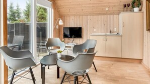 A modern kitchen with a TV, wooden ceiling, and a dining area with chairs and a table. - "Hejdie" - 150m from the sea by Interhome (Hals)