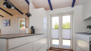 Eine Küche mit weißen Schränken, gefliestem Boden und einer Schiebeglasdoor zum Balkon.