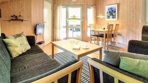 A cozy room with a sofa, a dining table with chairs, a TV, and a wooden ceiling. - "Frederikke" - 28km from the sea by Interhome (Toftlund)