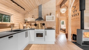 A modern log cabin interior with a kitchen, dining area, and a fireplace.