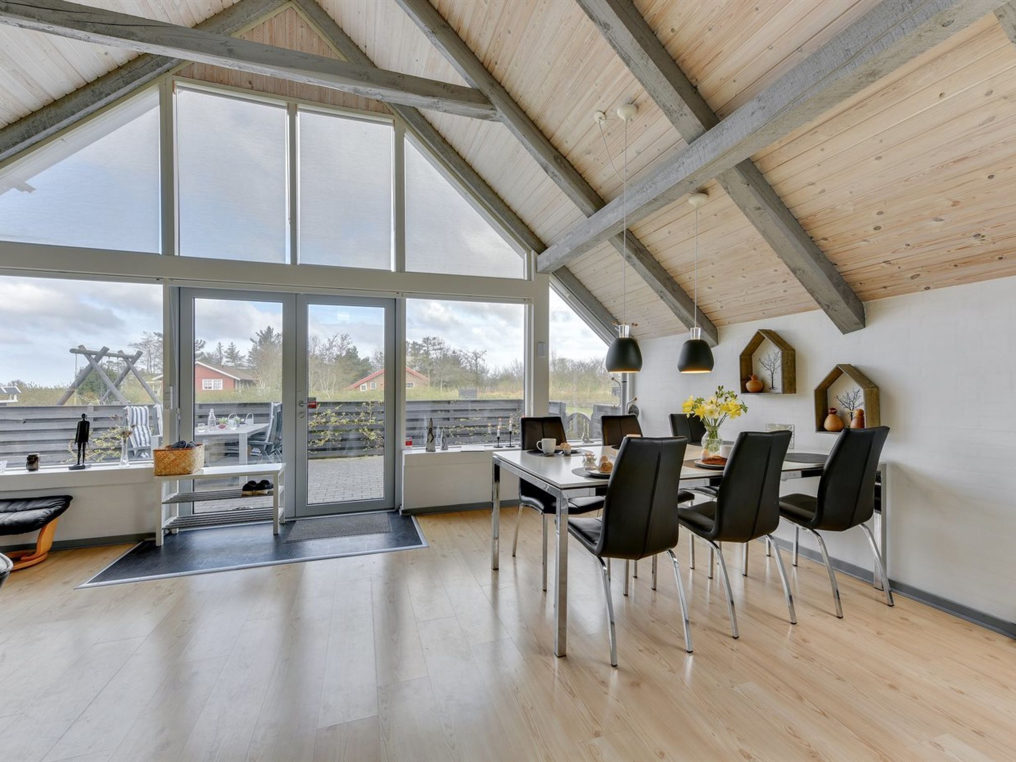 Una habitación amplia con techo alto, ventanas grandes y un comedor con sillas y una mesa.