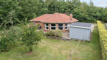 A single-story house with a red-tiled roof, a brick exterior, and a small attached shed.
