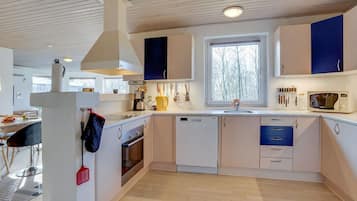 A modern kitchen with white cabinets, a built-in oven, and a window providing natural light.