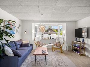 A modern living room with a sofa, chairs, a coffee table, a TV, and a large window with a view of houses. - "Amely" - 500m from the sea by Interhome (Sæby)