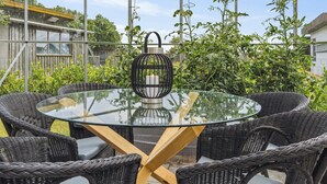 A glass-top round table with wicker chairs in a covered outdoor area.