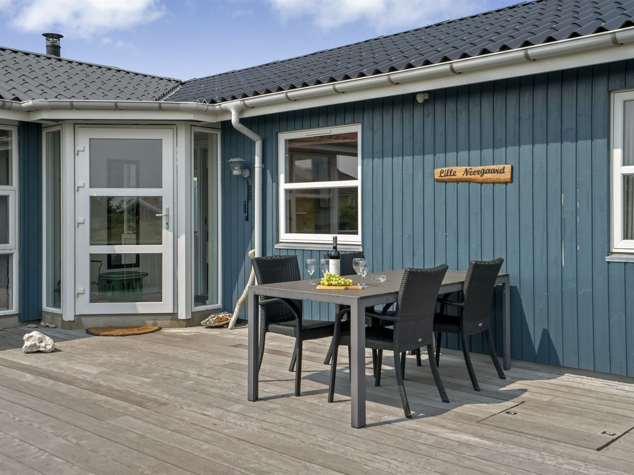 Een blauw gebouw met een bord waarop 'Little Nergard' staat en een tafel met stoelen buiten.