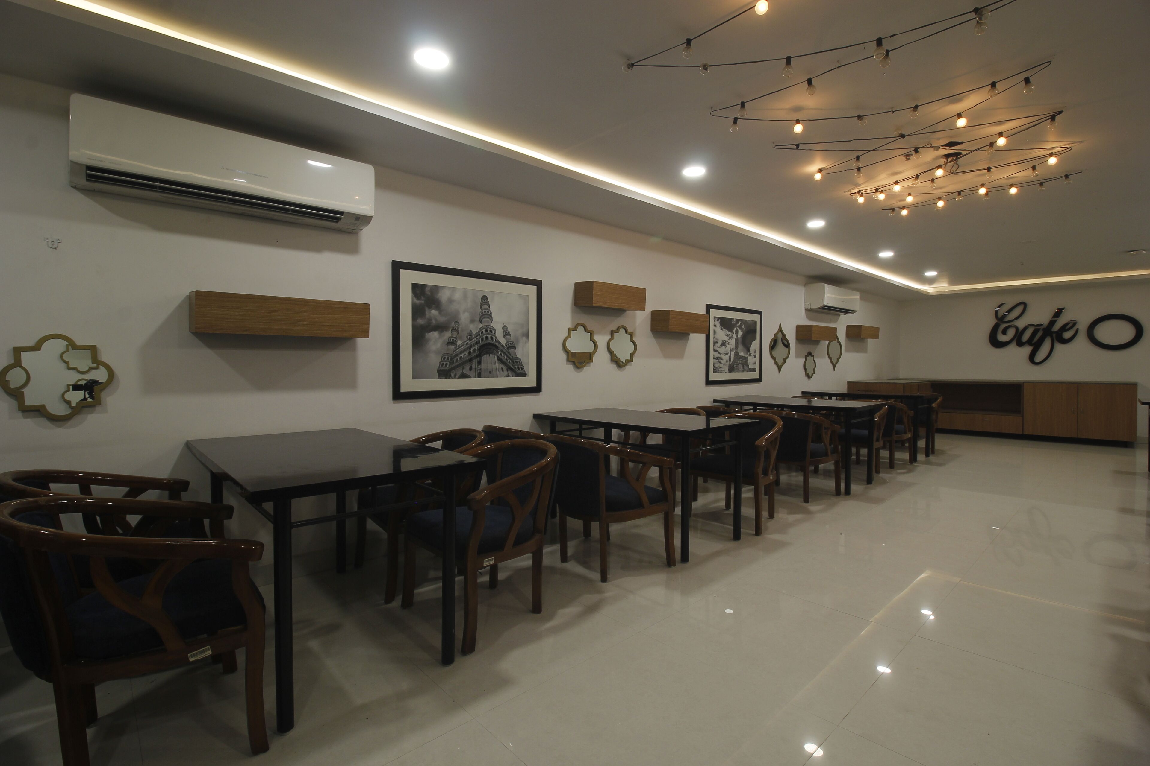 A cafe with wooden tables and chairs, wall-mounted air conditioning, and ceiling lights.