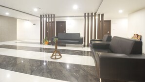 A modern lobby with a black leather sofa, a wooden coffee table, and a marble floor.