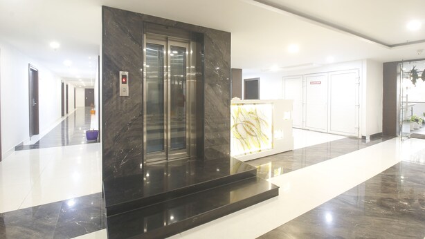 A modern hotel lobby with a marble elevator, a reception desk, and a 'DANGER' sign on a door.