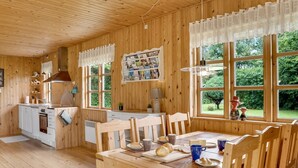 A cozy wooden cabin with a kitchen, dining area, and large windows offering a view of the greenery outside. - "Rikhard" - 75m from the sea by Interhome (Dannemare)