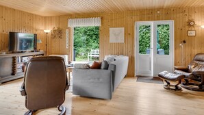 A wooden-paneled room with a television, a sofa, a recliner, and a door leading to a garden. - "Rikhard" - 75m from the sea by Interhome (Dannemare)