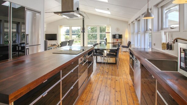 A modern kitchen with wooden countertops, a central island, and a large window providing natural light. - "Nienke" - 700m from the sea by Interhome (Løkken)