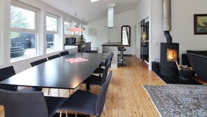 A modern kitchen with a large dining table, a wood-burning stove, and large windows. - "Nienke" - 700m from the sea by Interhome (Løkken)